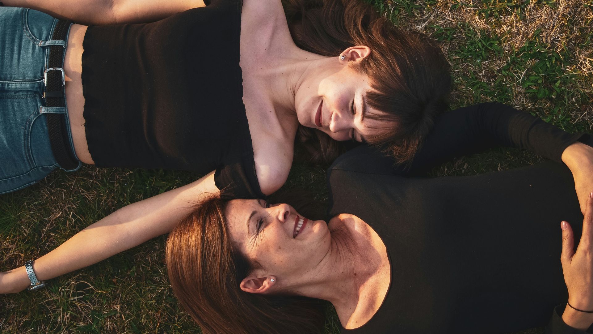 woman in black sleeveless dress lying on green grass field