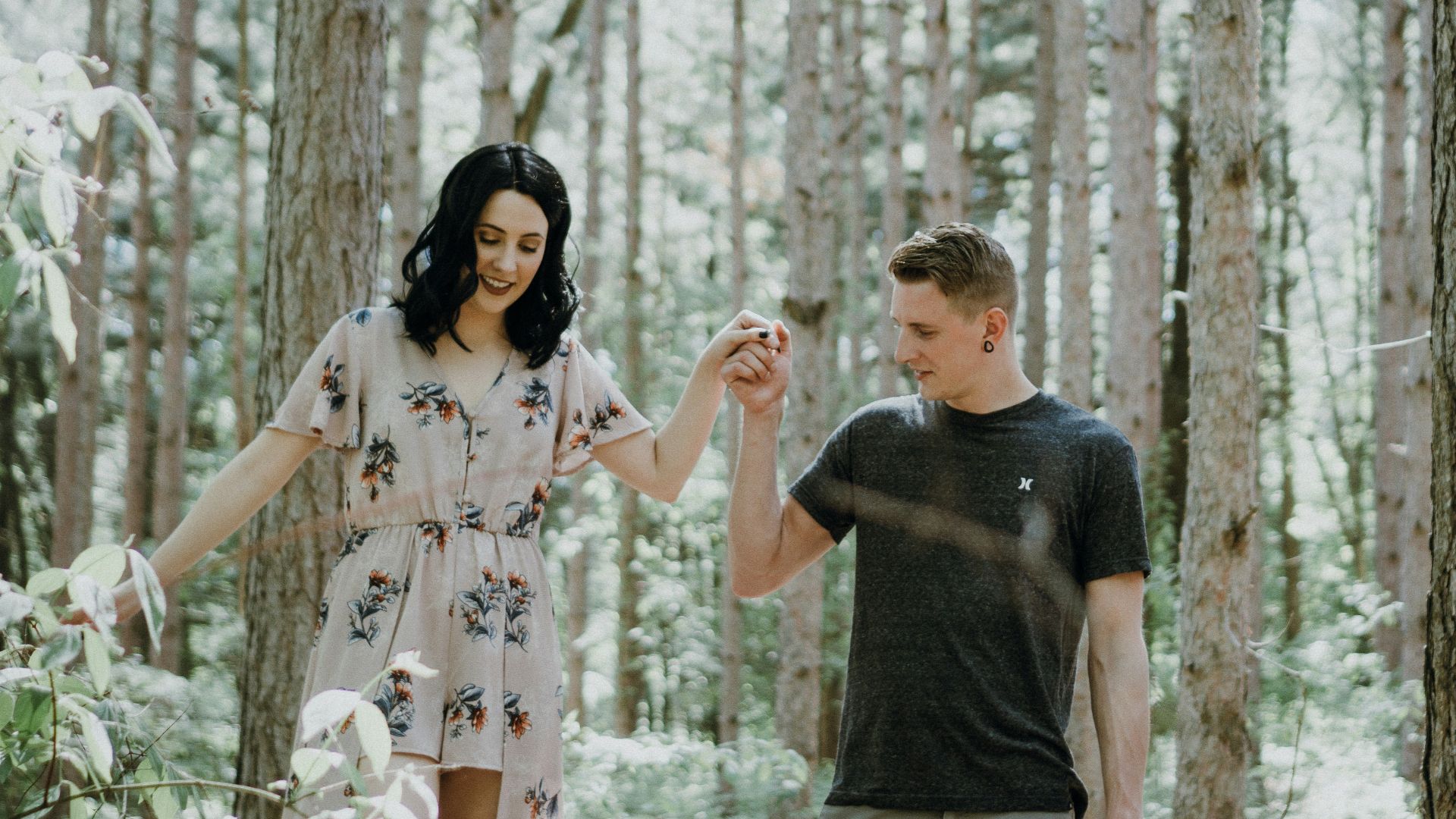 man holding hands with woman near trees