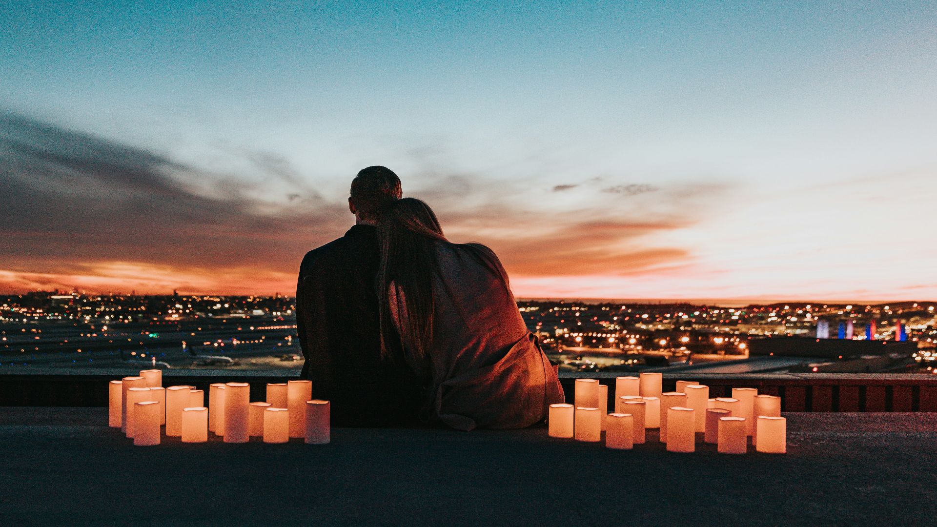 couple sitting on the field facing the city