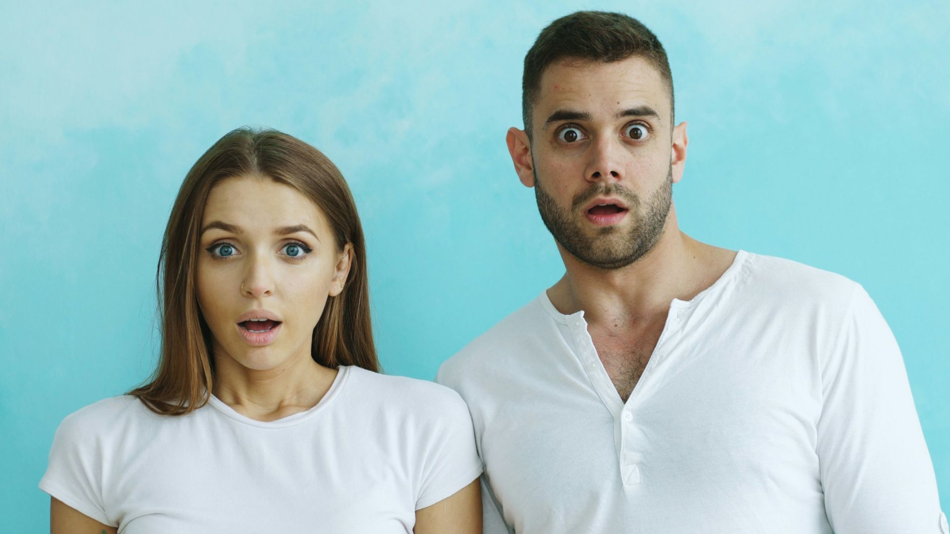 Couple with shocked expressions against blue background