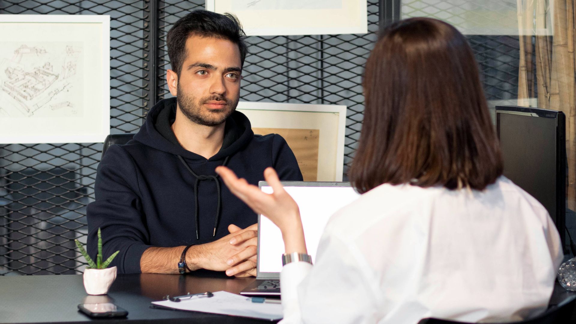 a man sitting at a desk talking to a woman