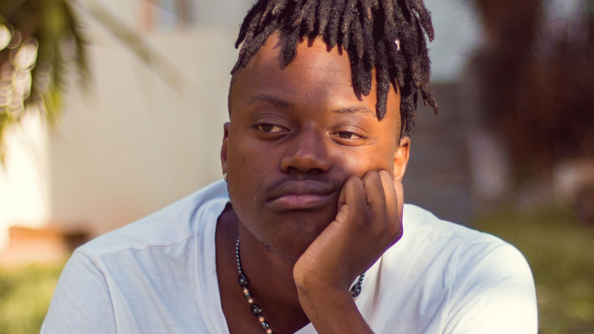 man in white crew neck t-shirt sitting on brown wooden chair