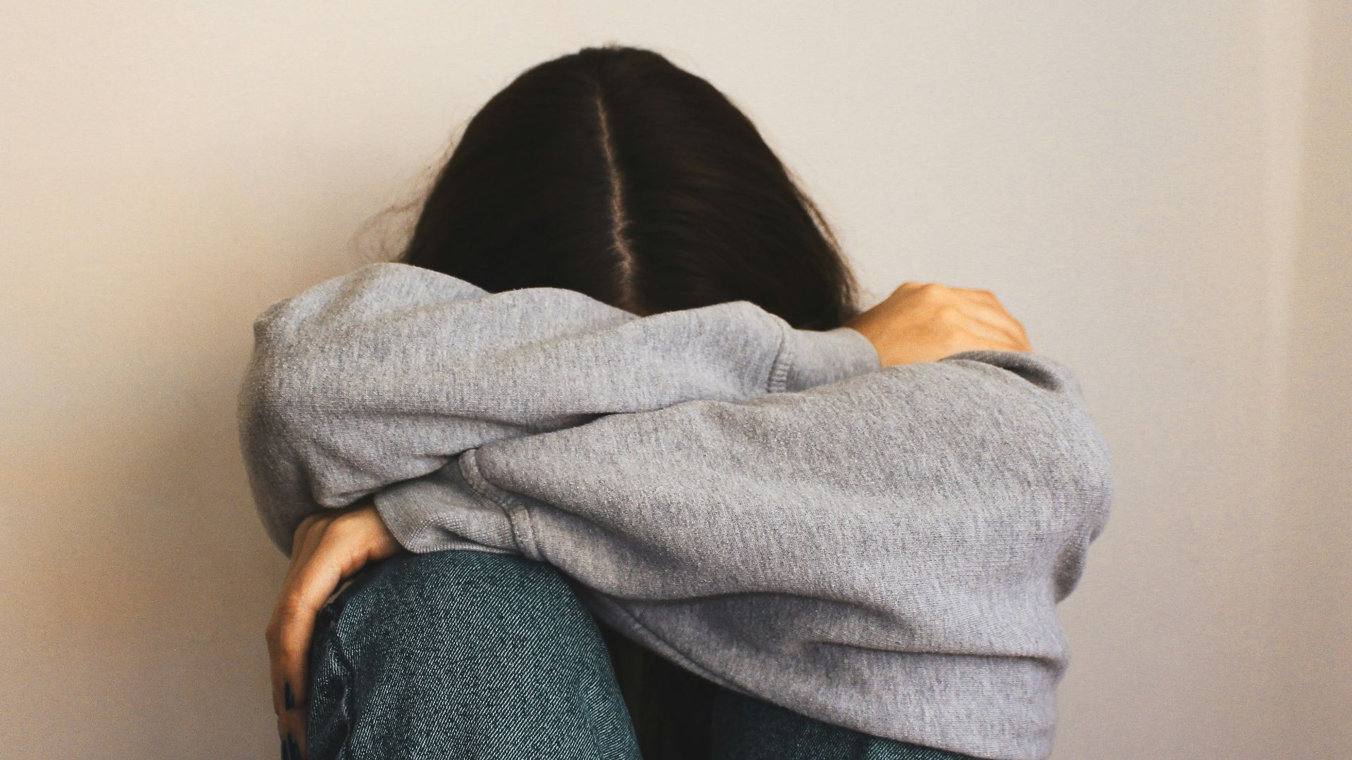 a woman sitting on the floor with her arms wrapped around her head