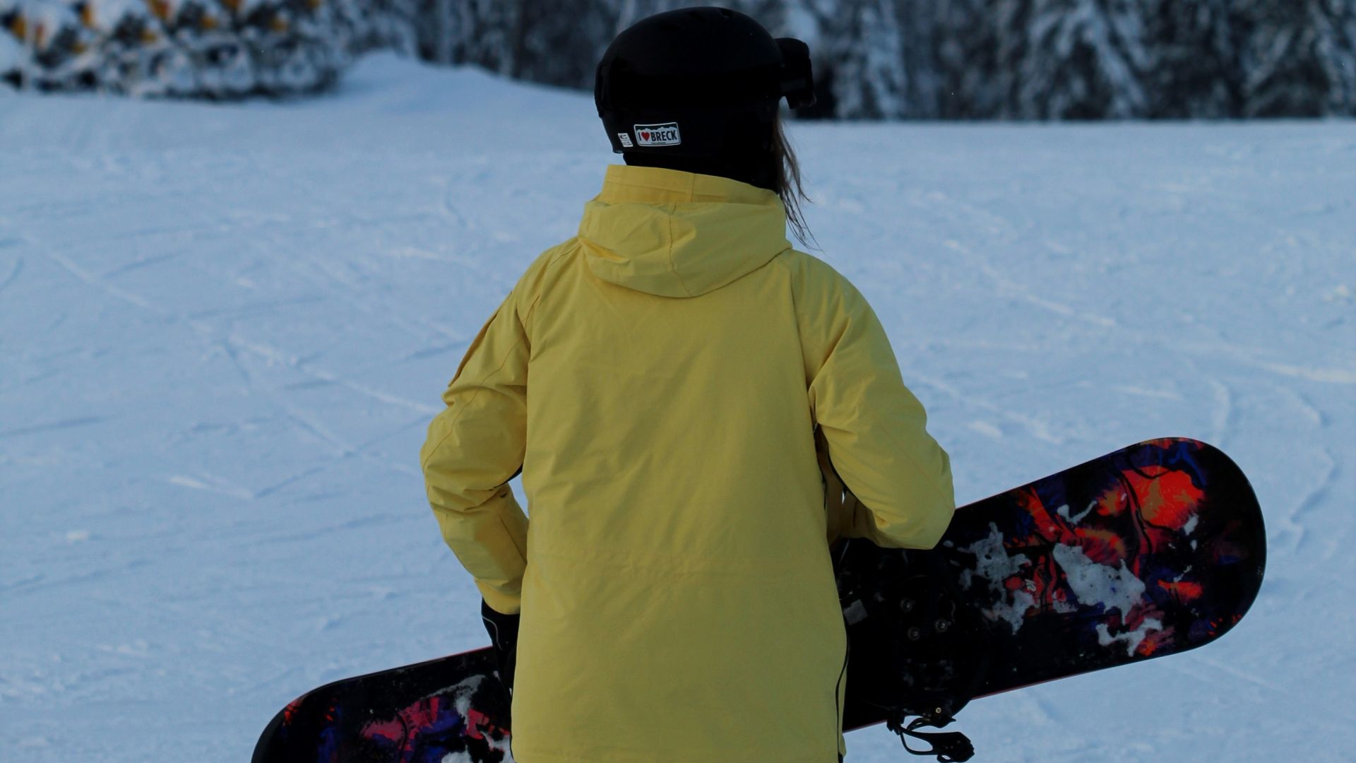 person in green jacket and black knit cap sitting on snow covered ground during daytime