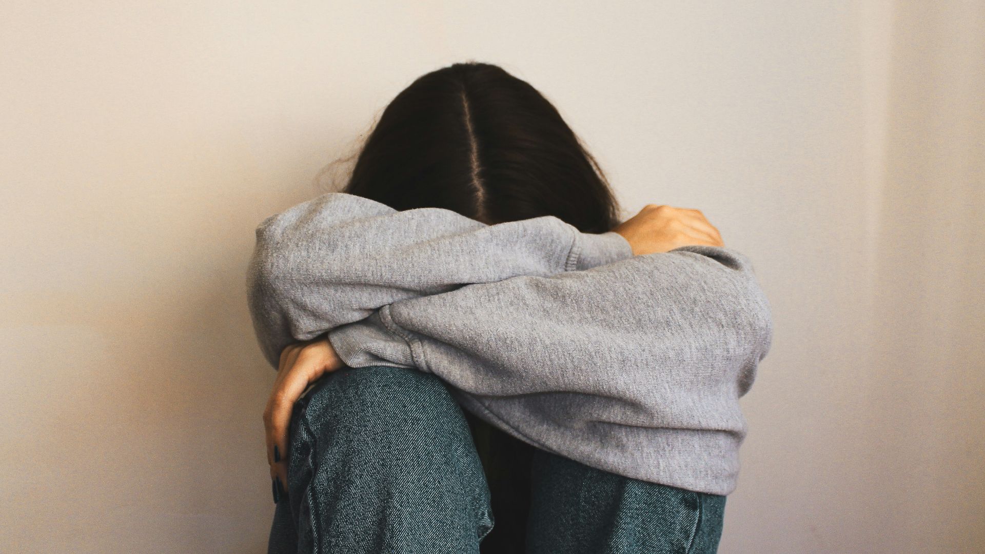 a woman sitting on the floor with her arms wrapped around her head
