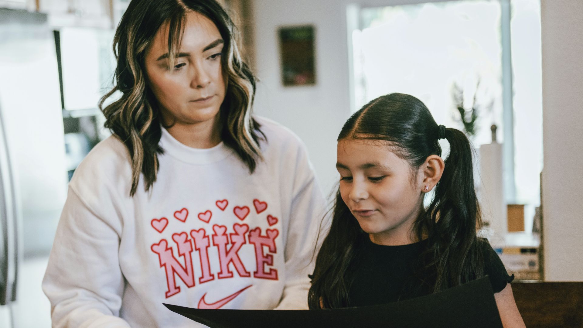 a woman standing next to a little girl in a kitchen