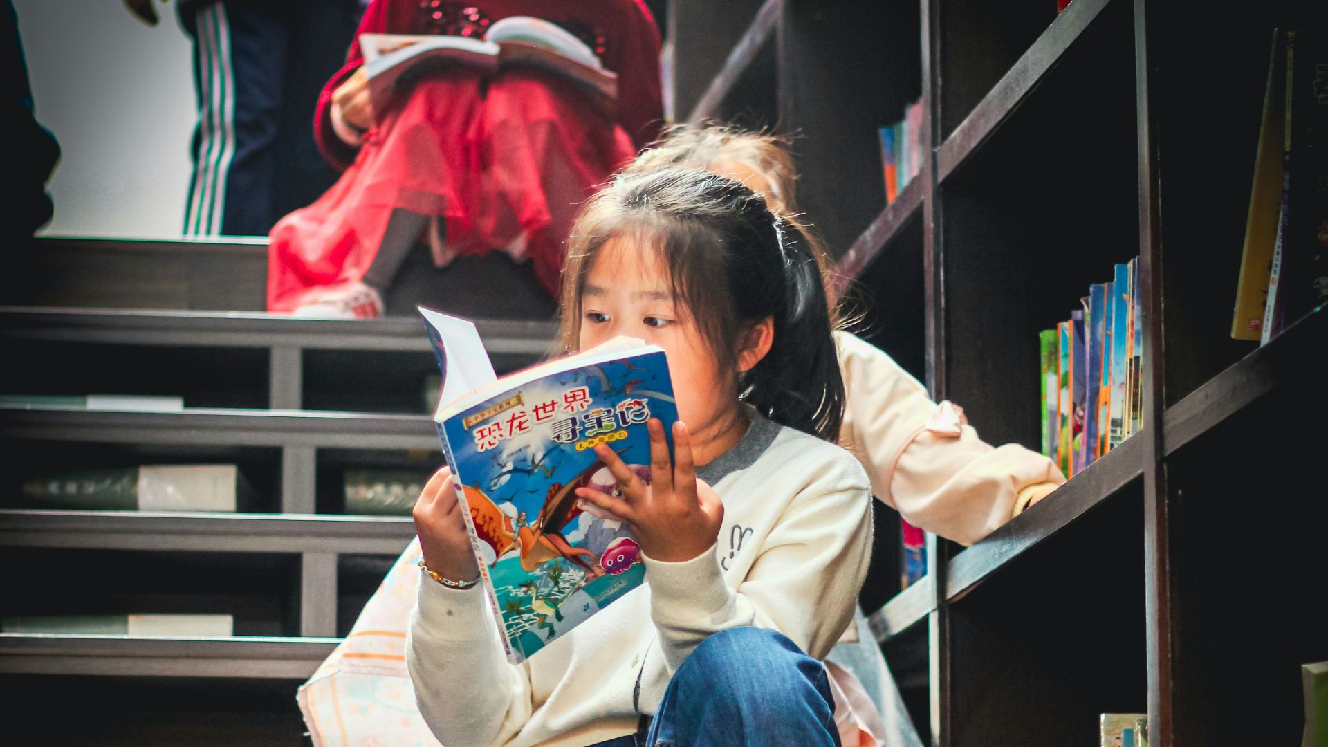 Young girl reads a book on library stairs