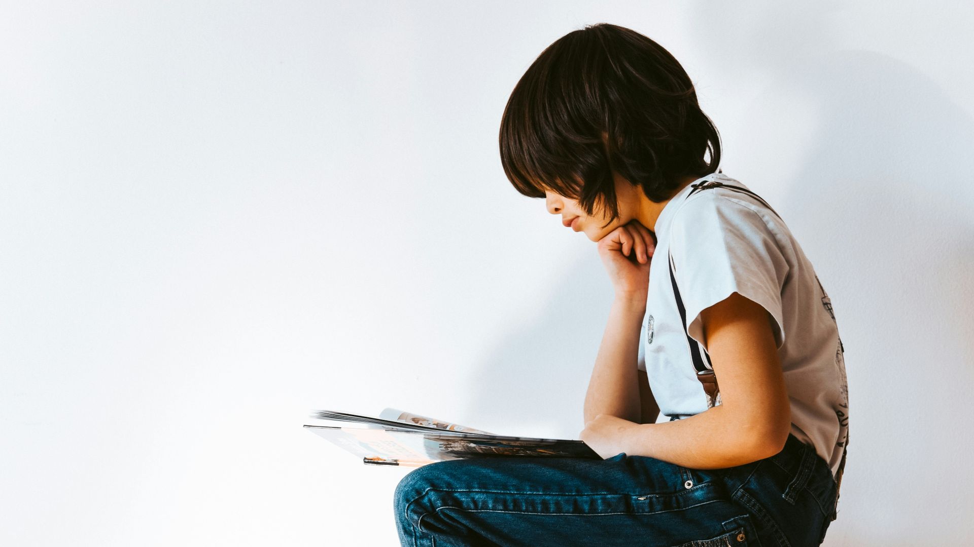 woman in gray t-shirt and blue denim jeans reading book