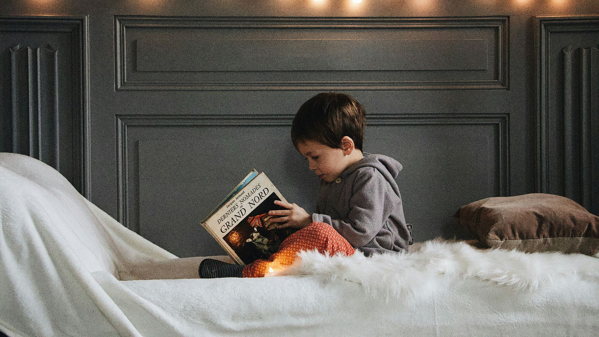 boy reading book on bed