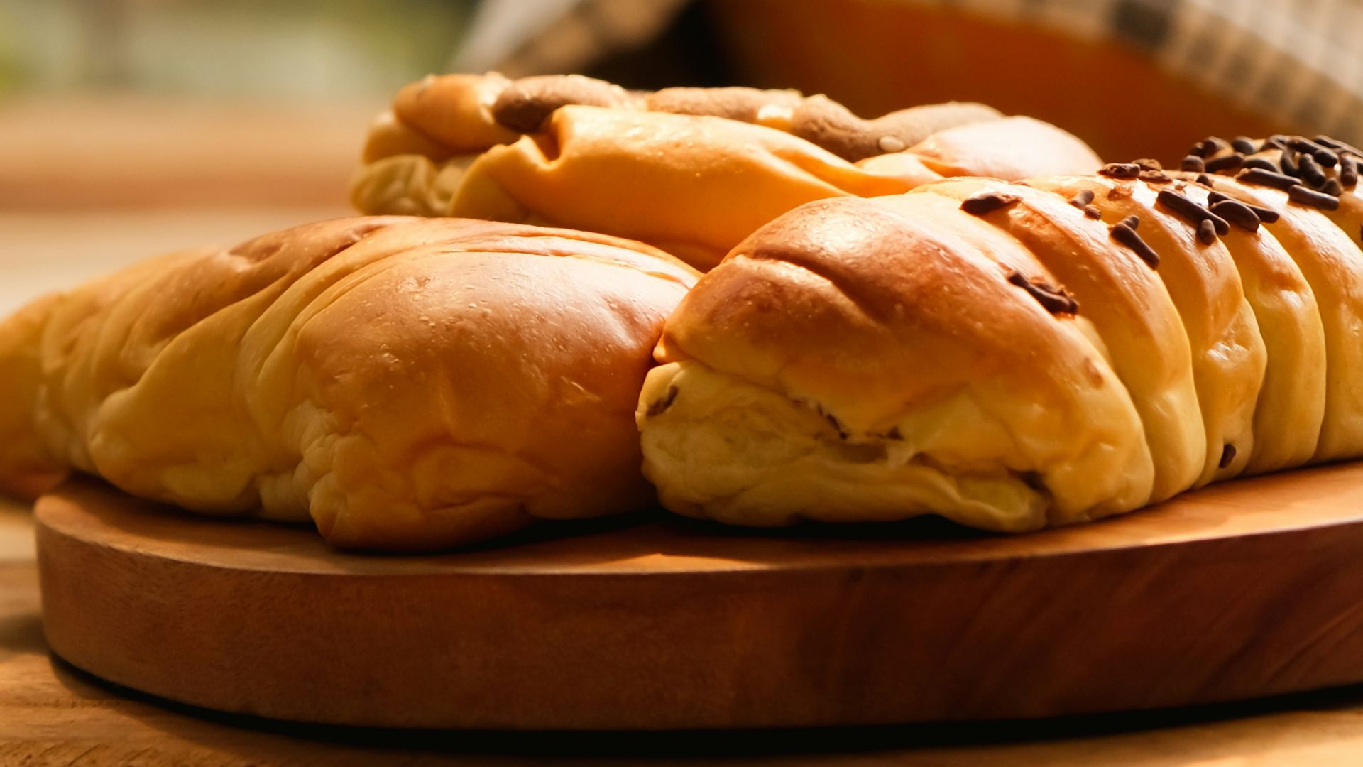 a wooden plate topped with bread next to a glass of milk
