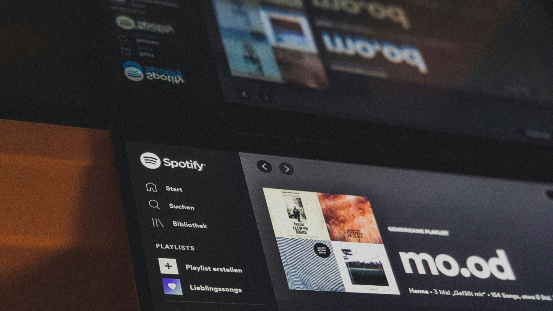 Spotify is open on two laptops displaying music.