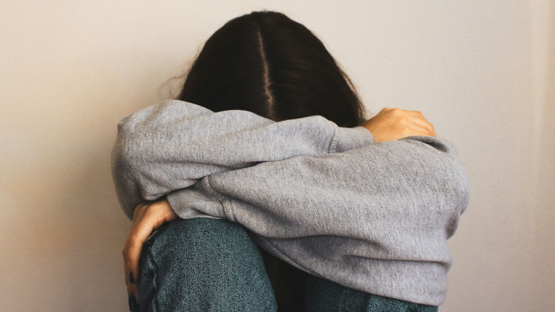 a woman sitting on the floor with her arms wrapped around her head