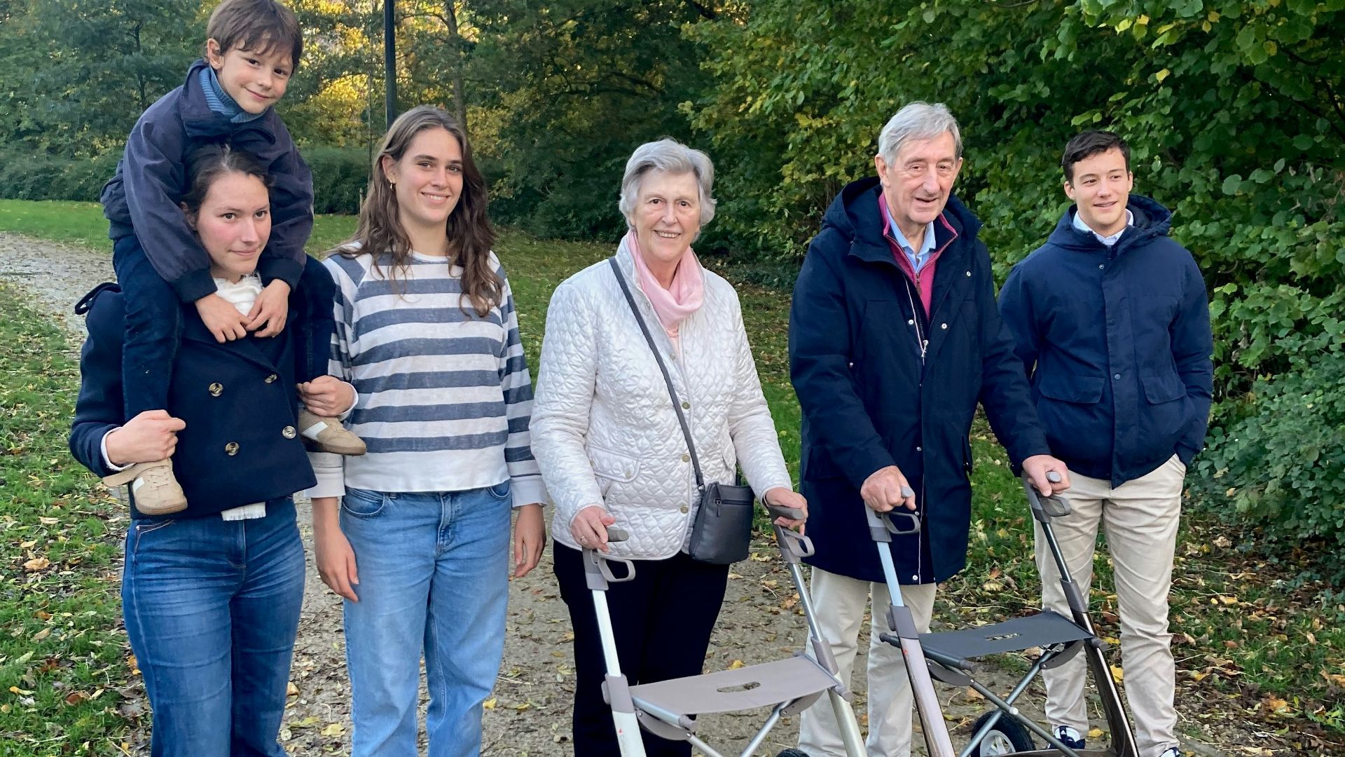 A multi-generational family walking in a park.