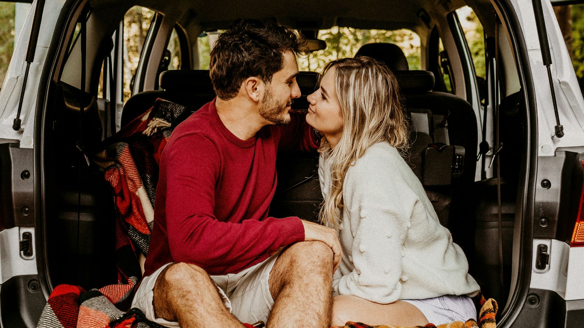 man and woman sitting on car's trunk