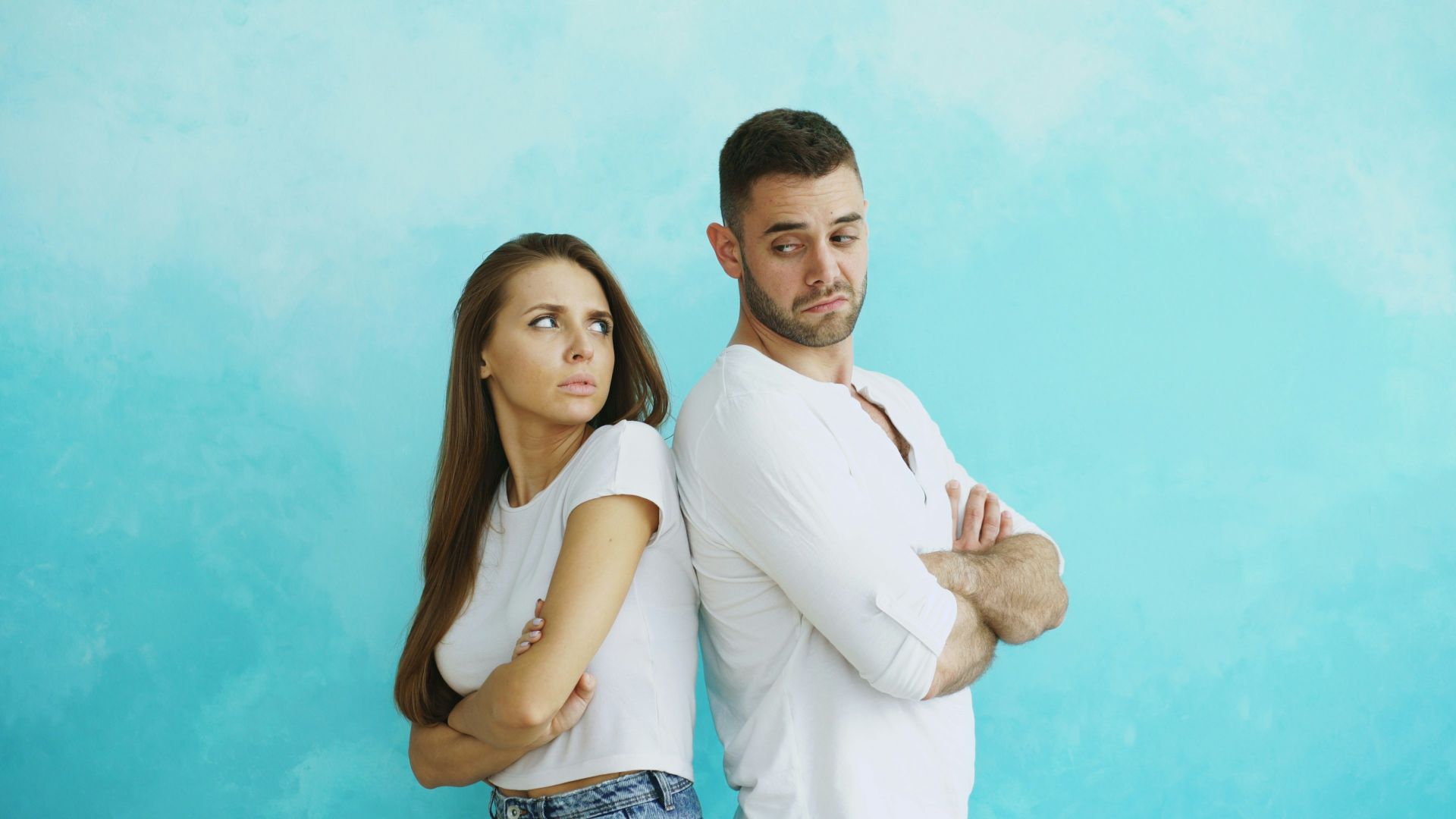 Couple standing back to back with arms crossed