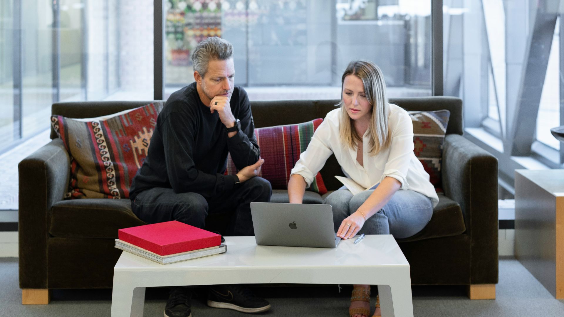 man and woman sitting on couch using macbook