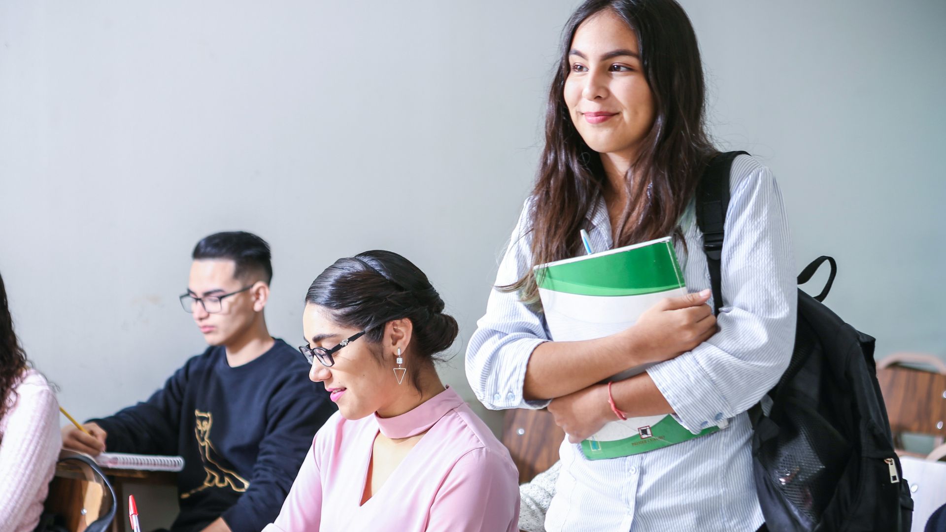 woman carrying white and green textbook