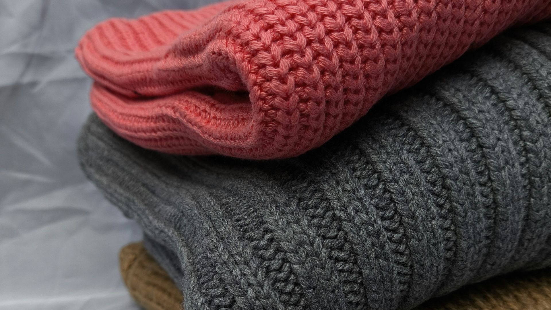 A stack of three knitted sweaters sitting on top of each other