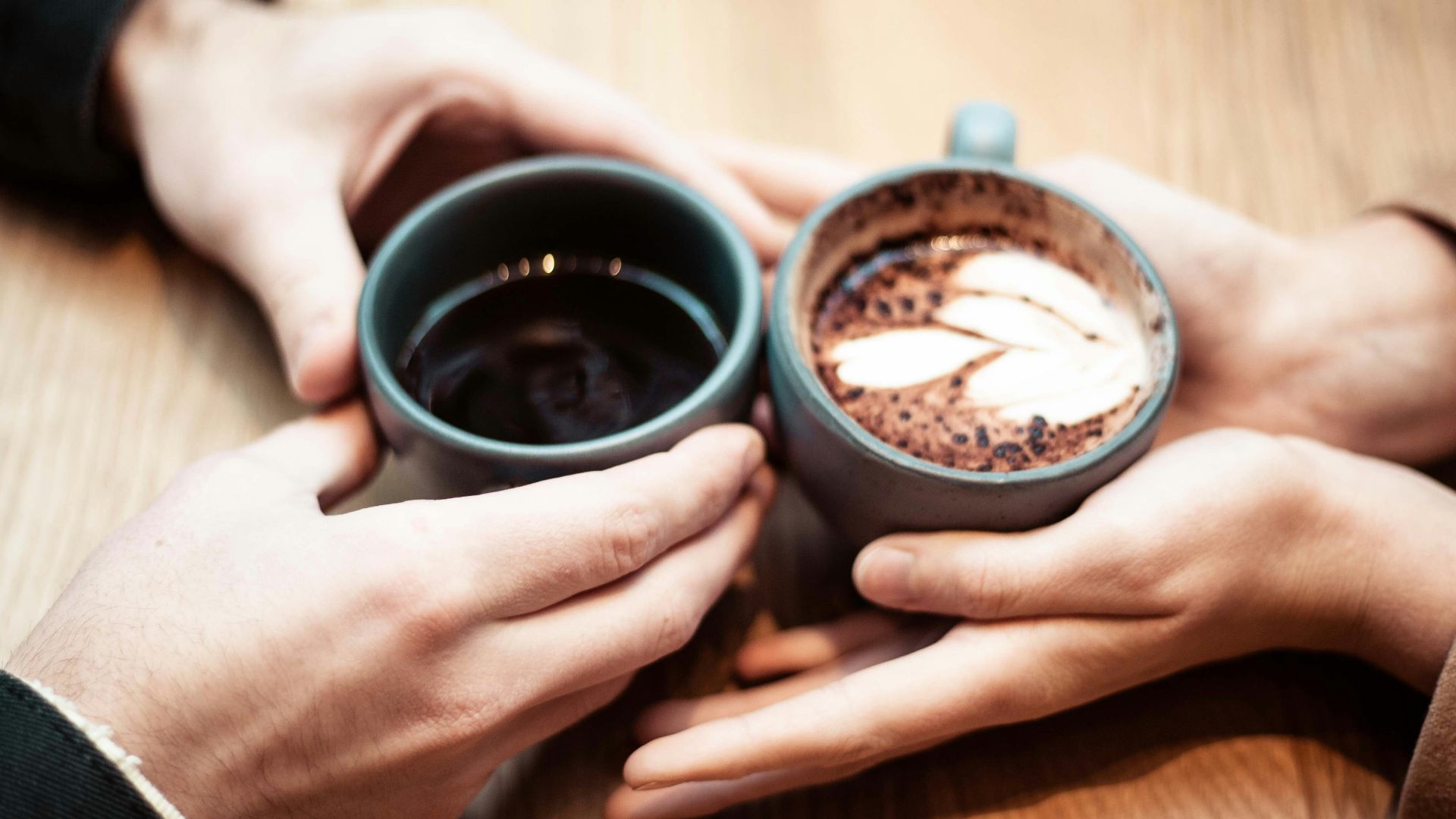 two person holding ceramic mugs with coffee