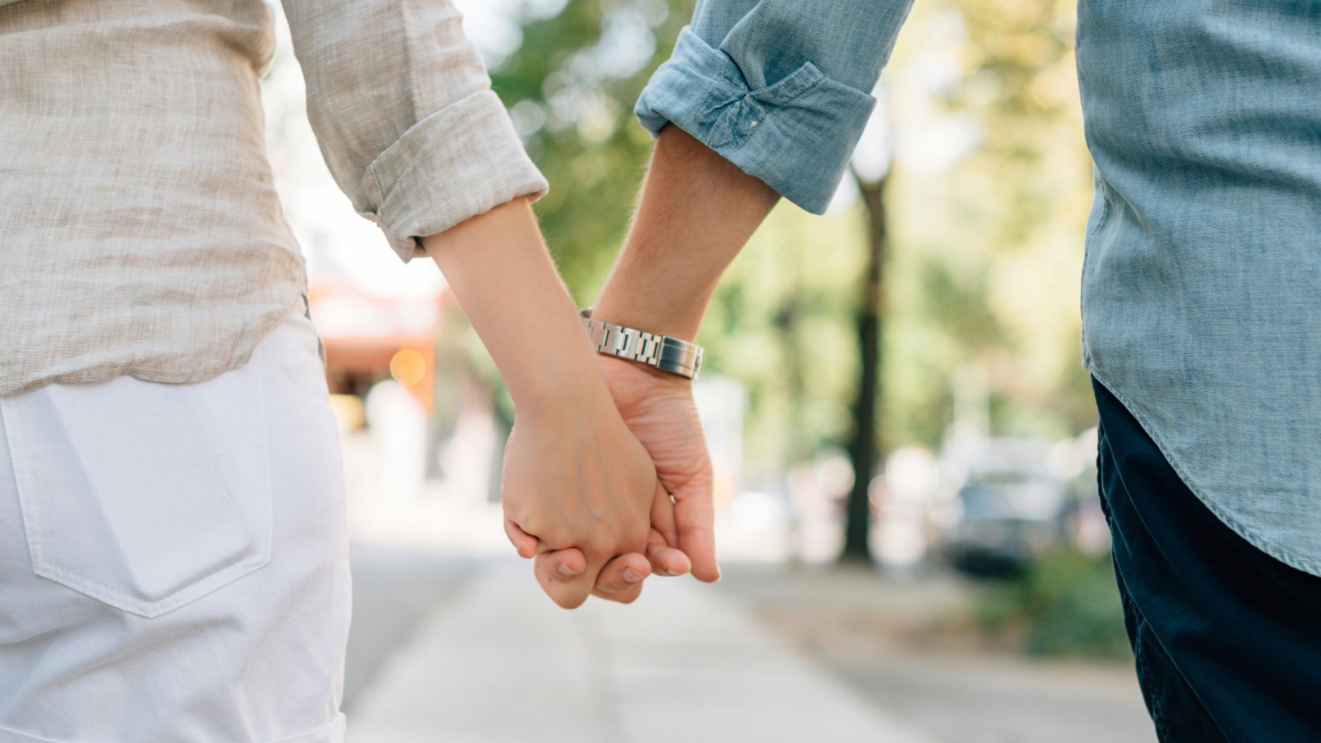 man and woman holding hands together in walkway during daytime