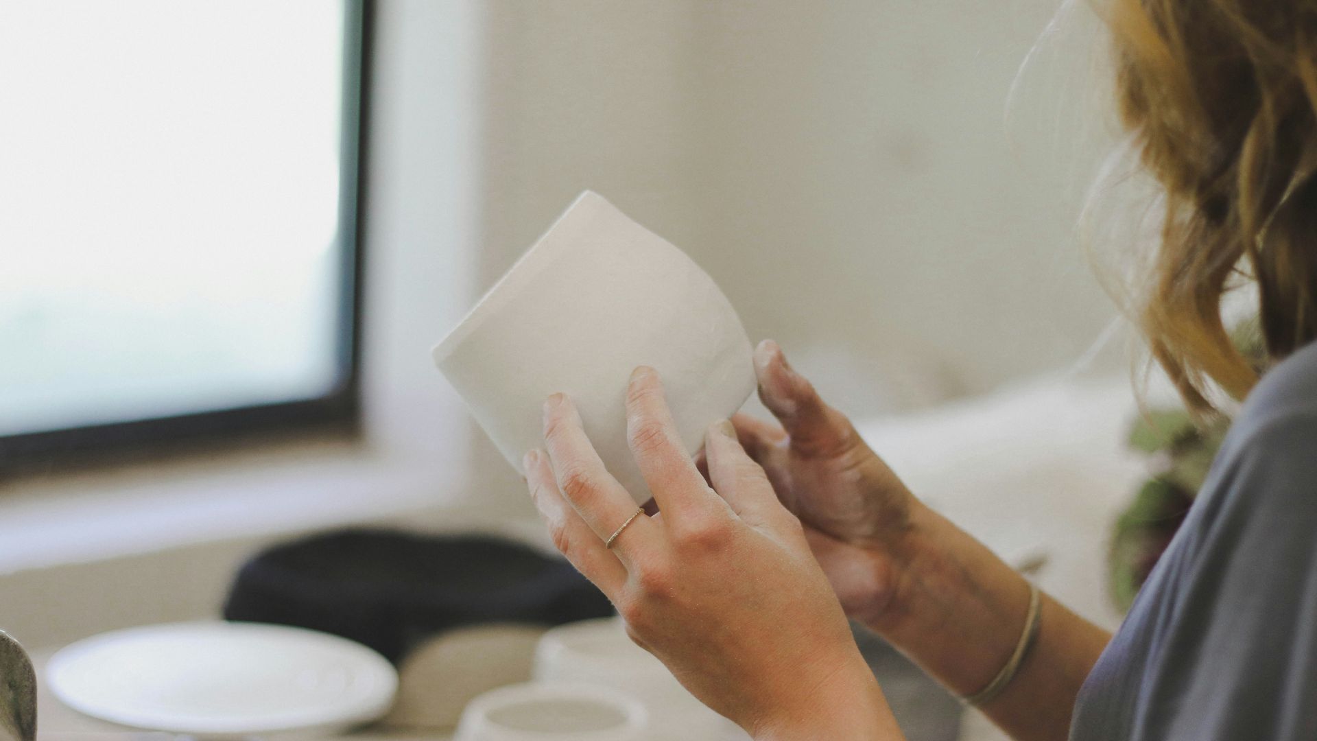 woman standing while making clay pot during daytime