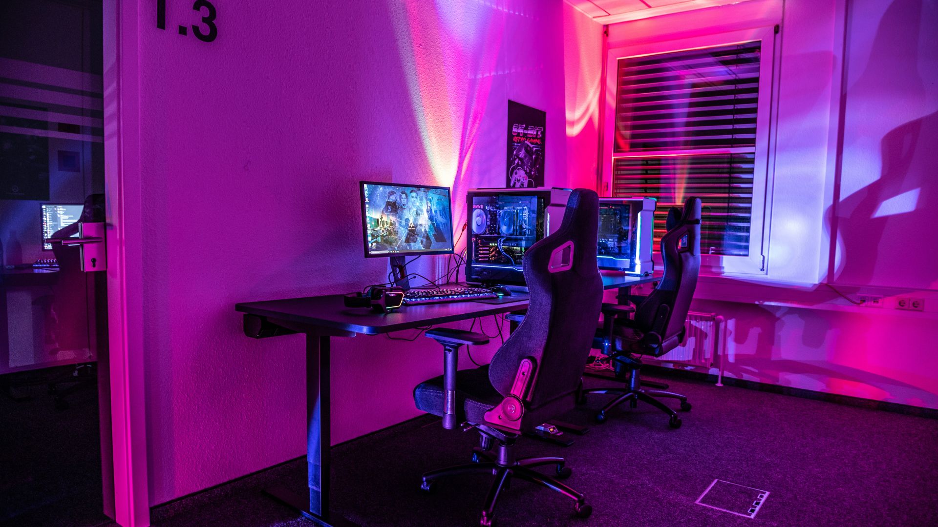 a room with a desk, computer, and two monitors