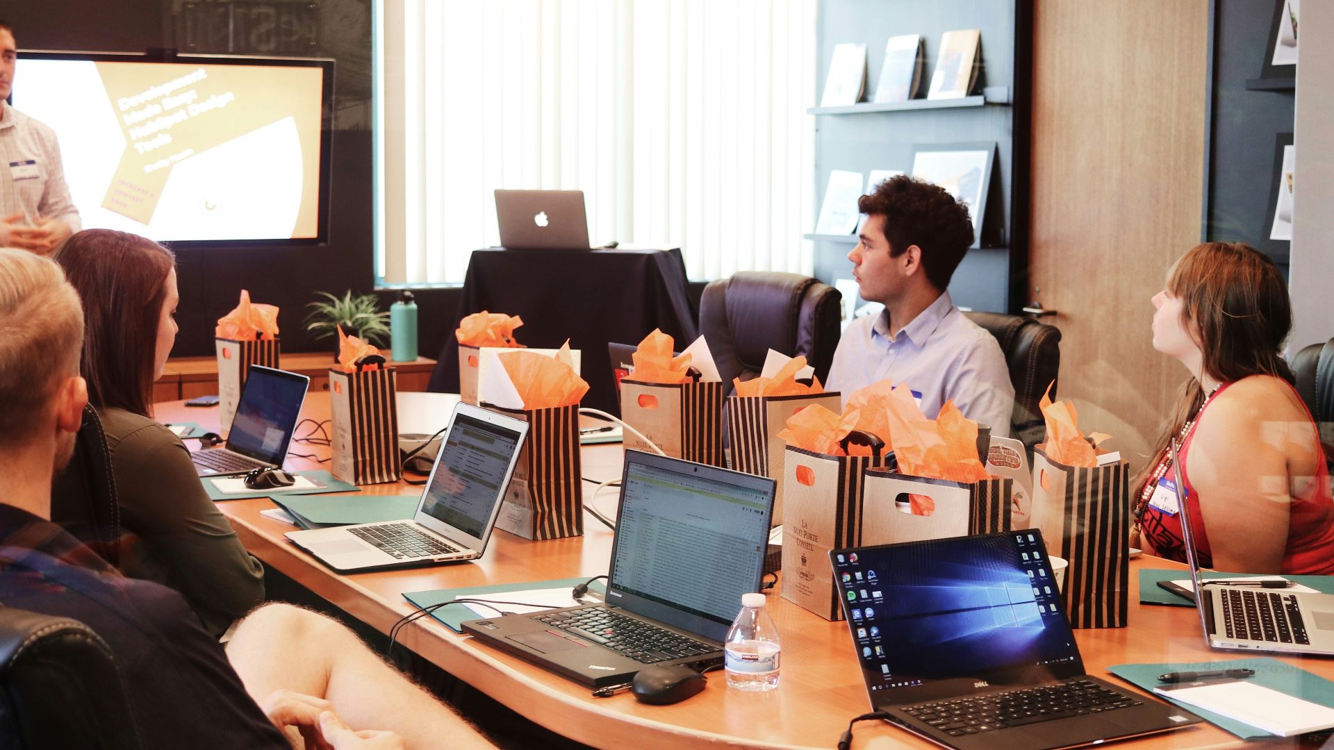 man standing in front of people sitting beside table with laptop computers