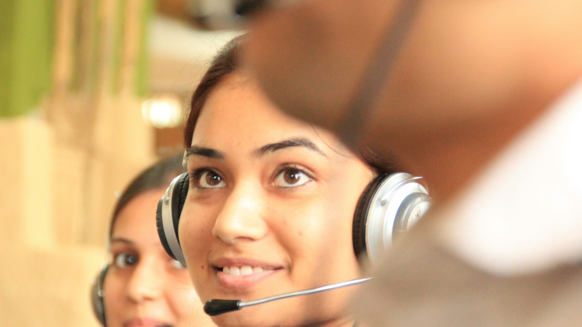 woman in black headphones holding black and silver headphones