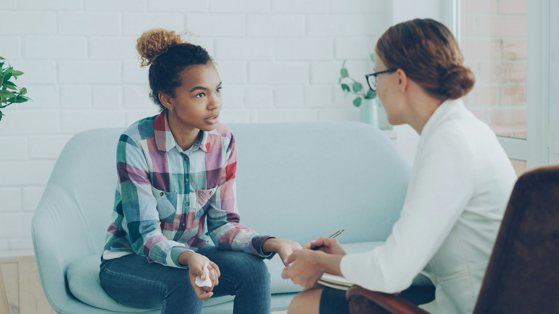 Therapist talking to a young woman on couch.