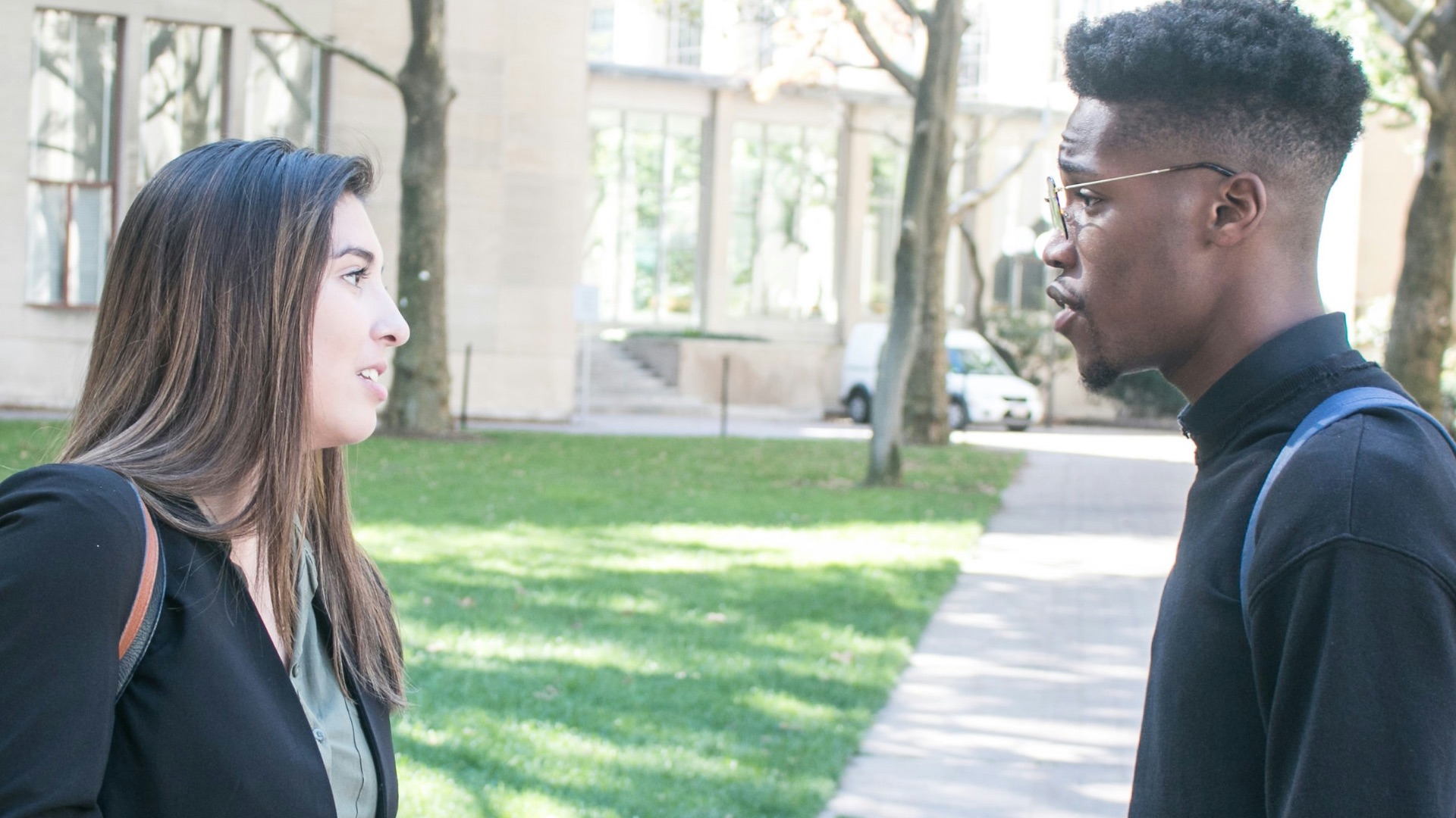 a man standing next to a woman on a sidewalk