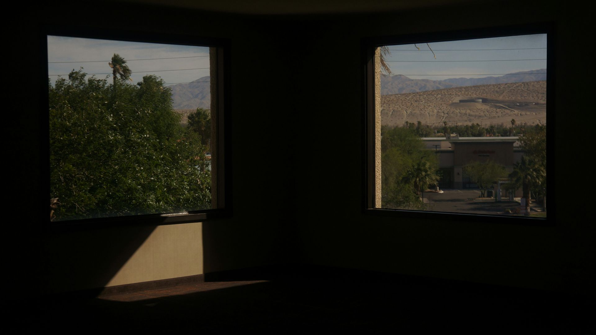 two windows in a dark room with mountains in the background