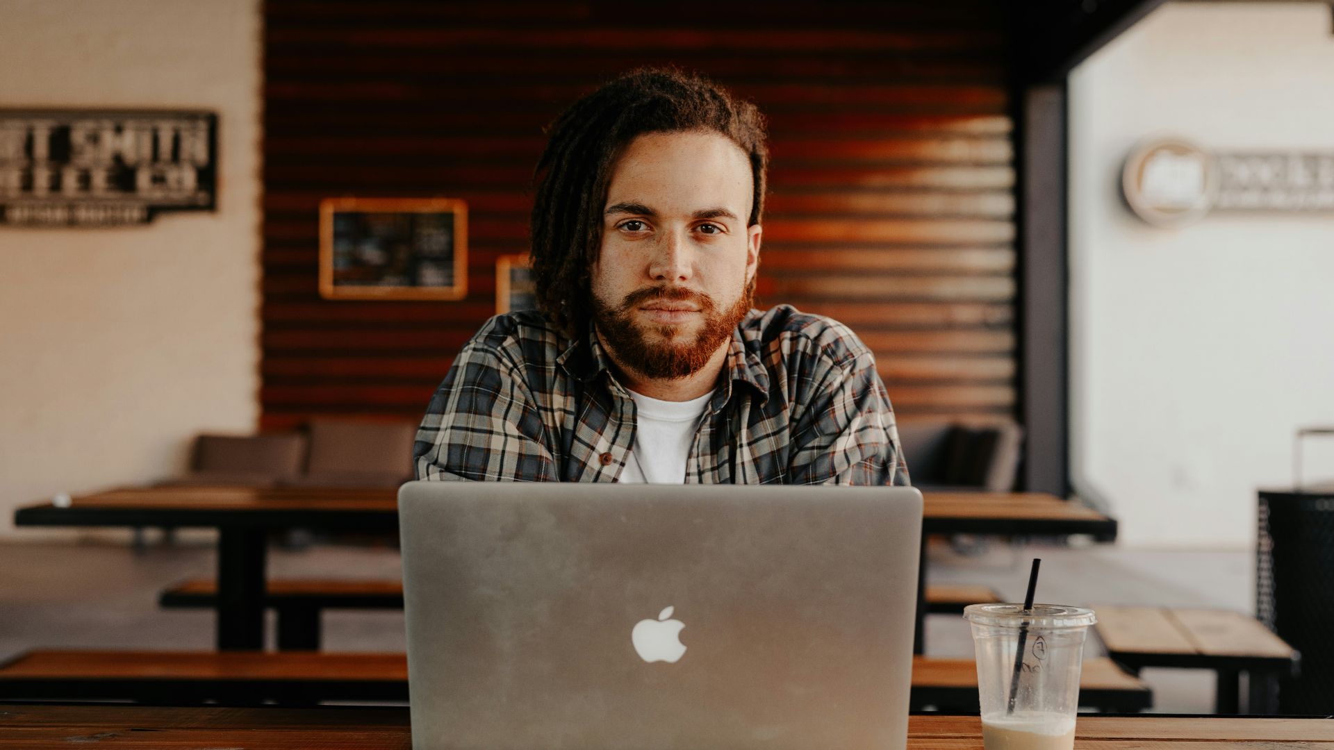man in black and white plaid dress shirt using silver macbook