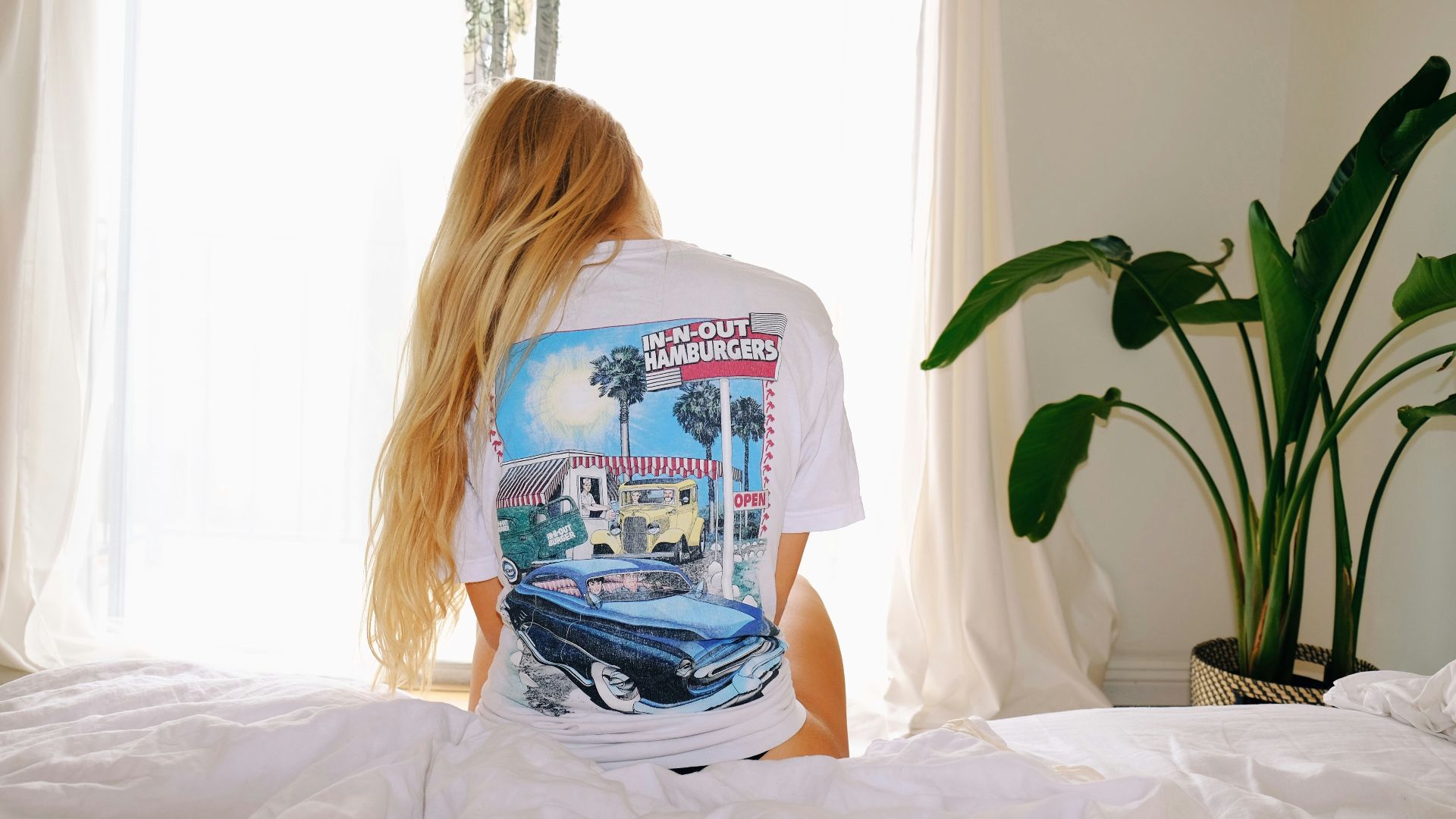 woman in white and blue crew neck t-shirt sitting on bed
