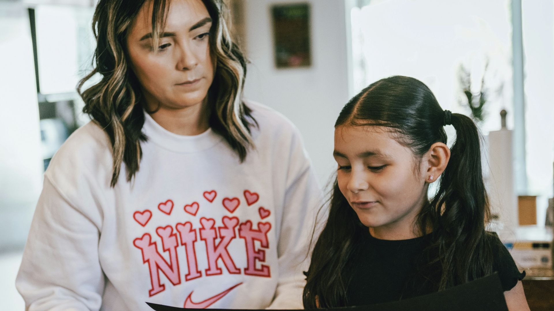 a woman standing next to a little girl in a kitchen