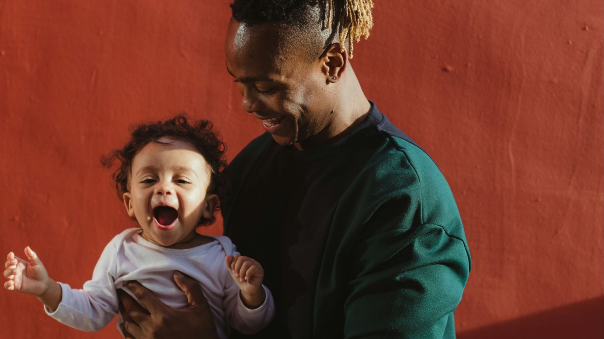 smiling man carrying child and playing