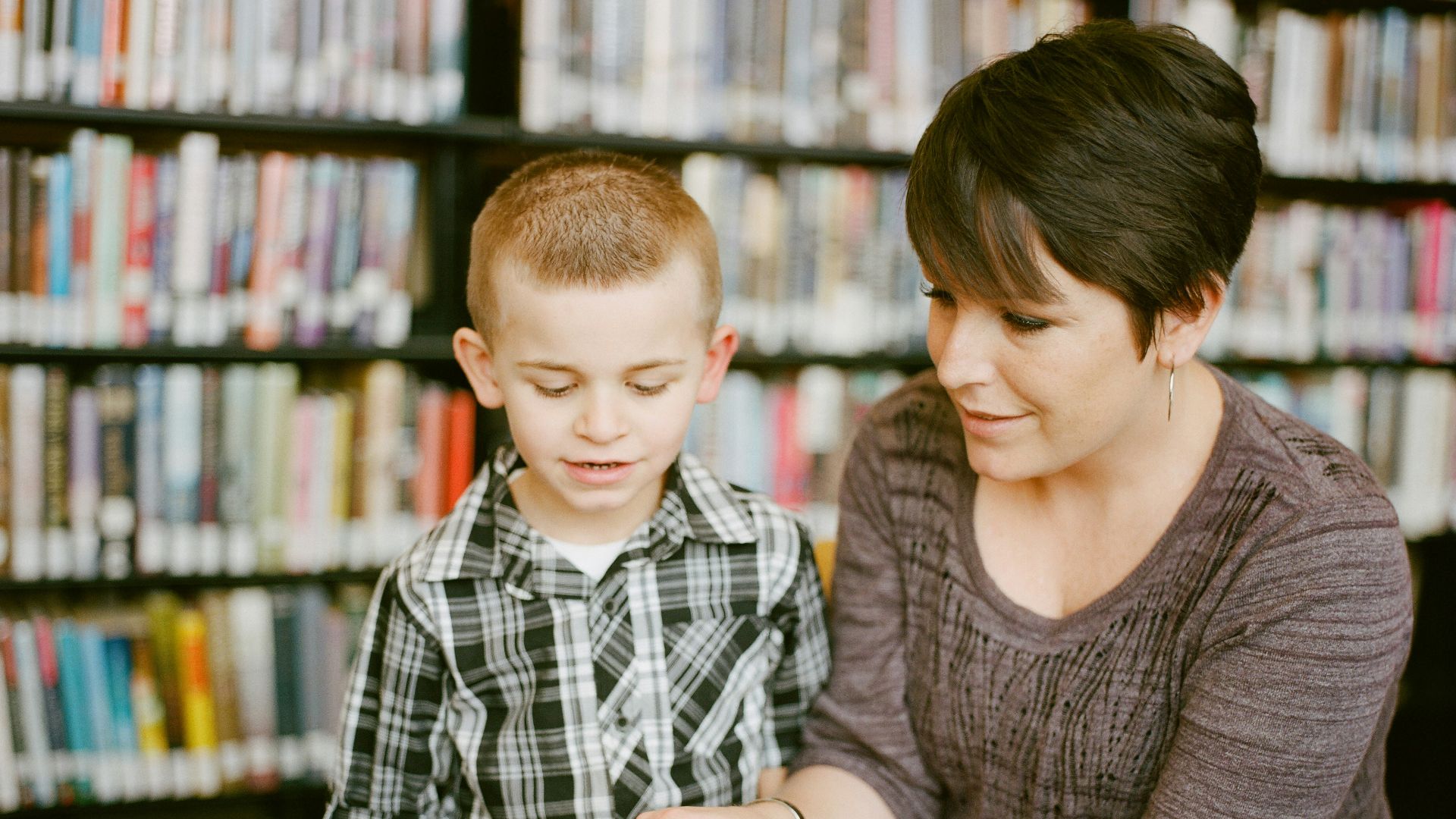 boy in gray sweater beside boy in gray and white plaid dress shirt