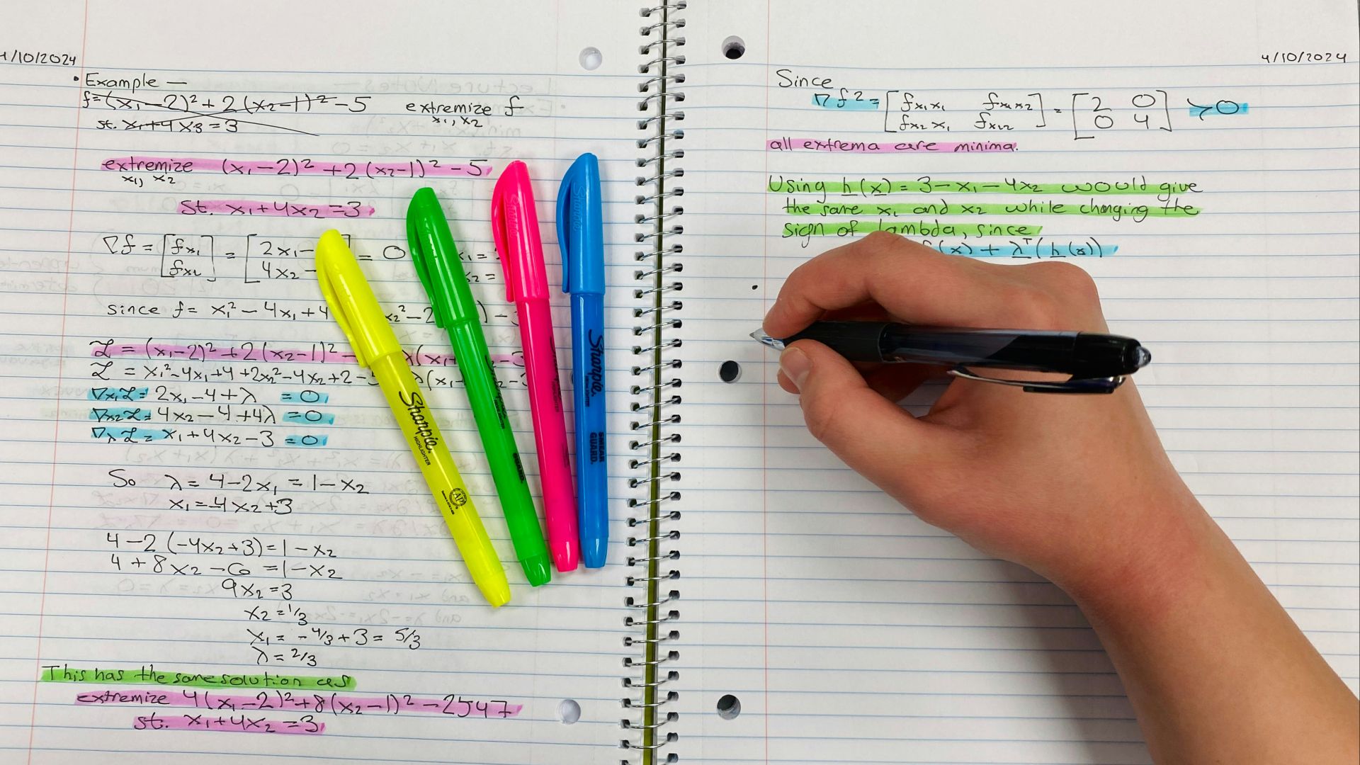 a person writing on a notebook with colored pens