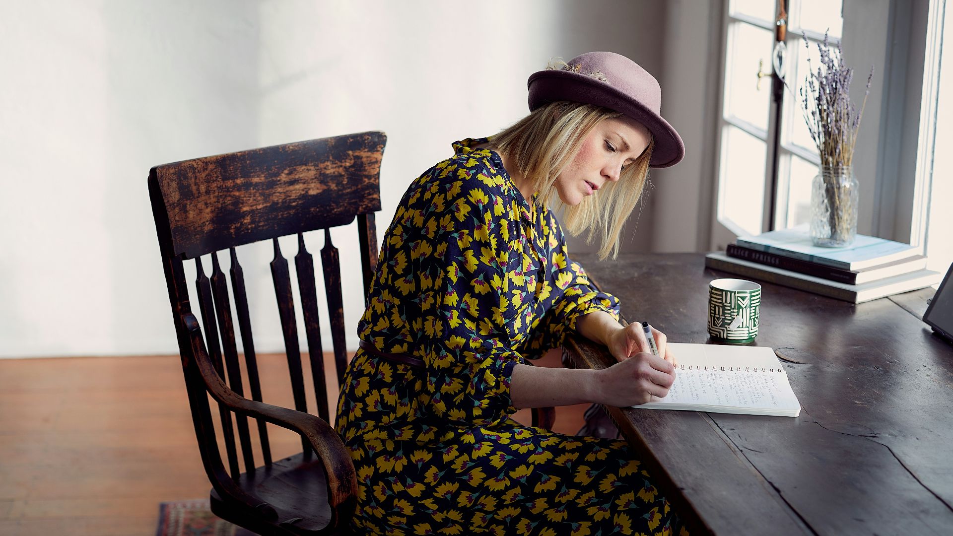 woman in yellow and black floral dress sitting on brown wooden chair
