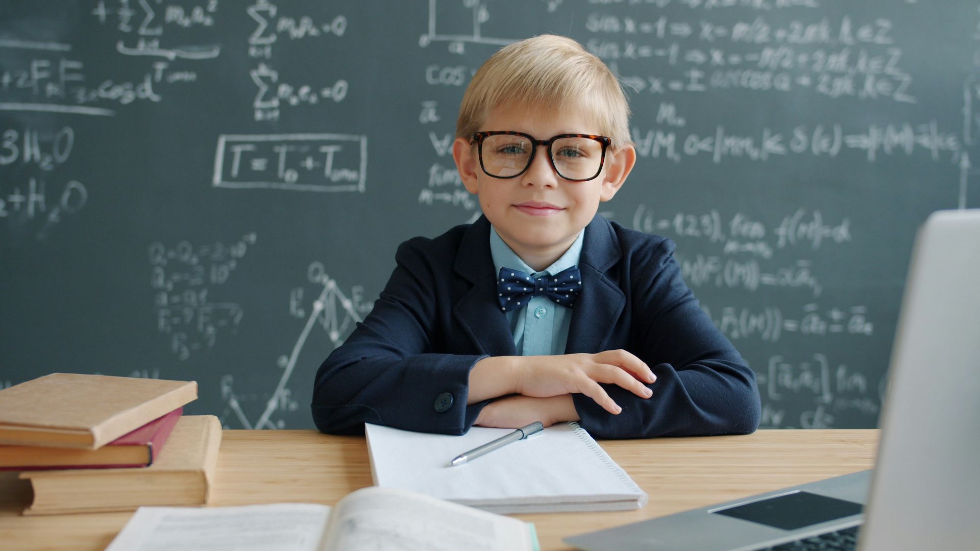 Young boy in glasses at desk with math equations