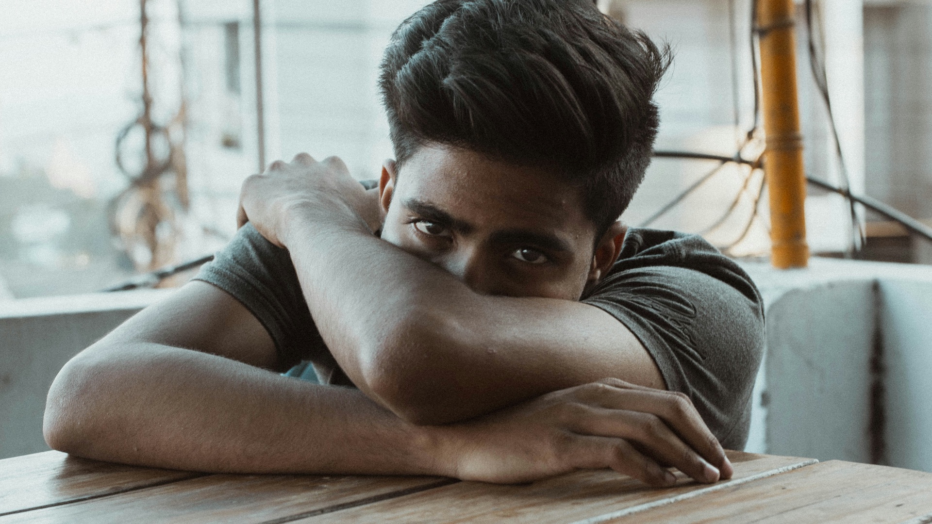 man in black t-shirt leaning on wooden table