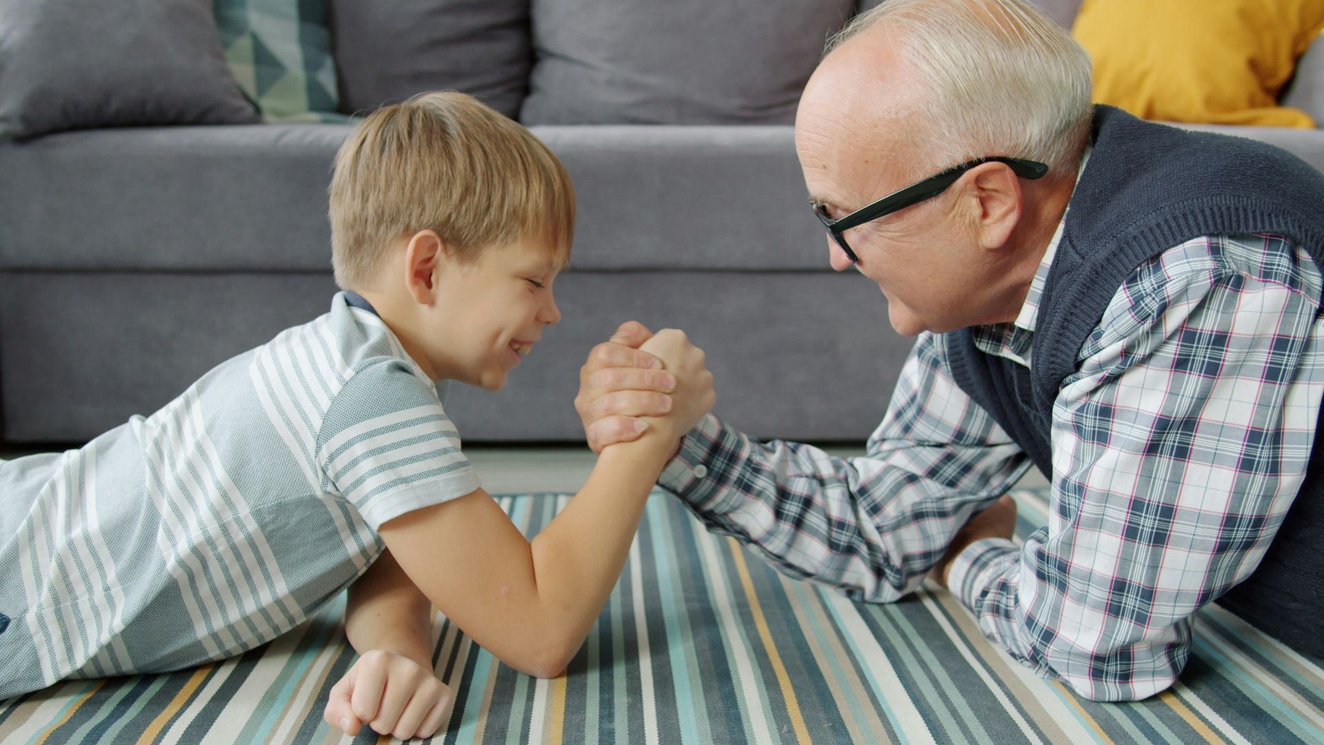 Grandfather and grandson arm wrestling on the floor