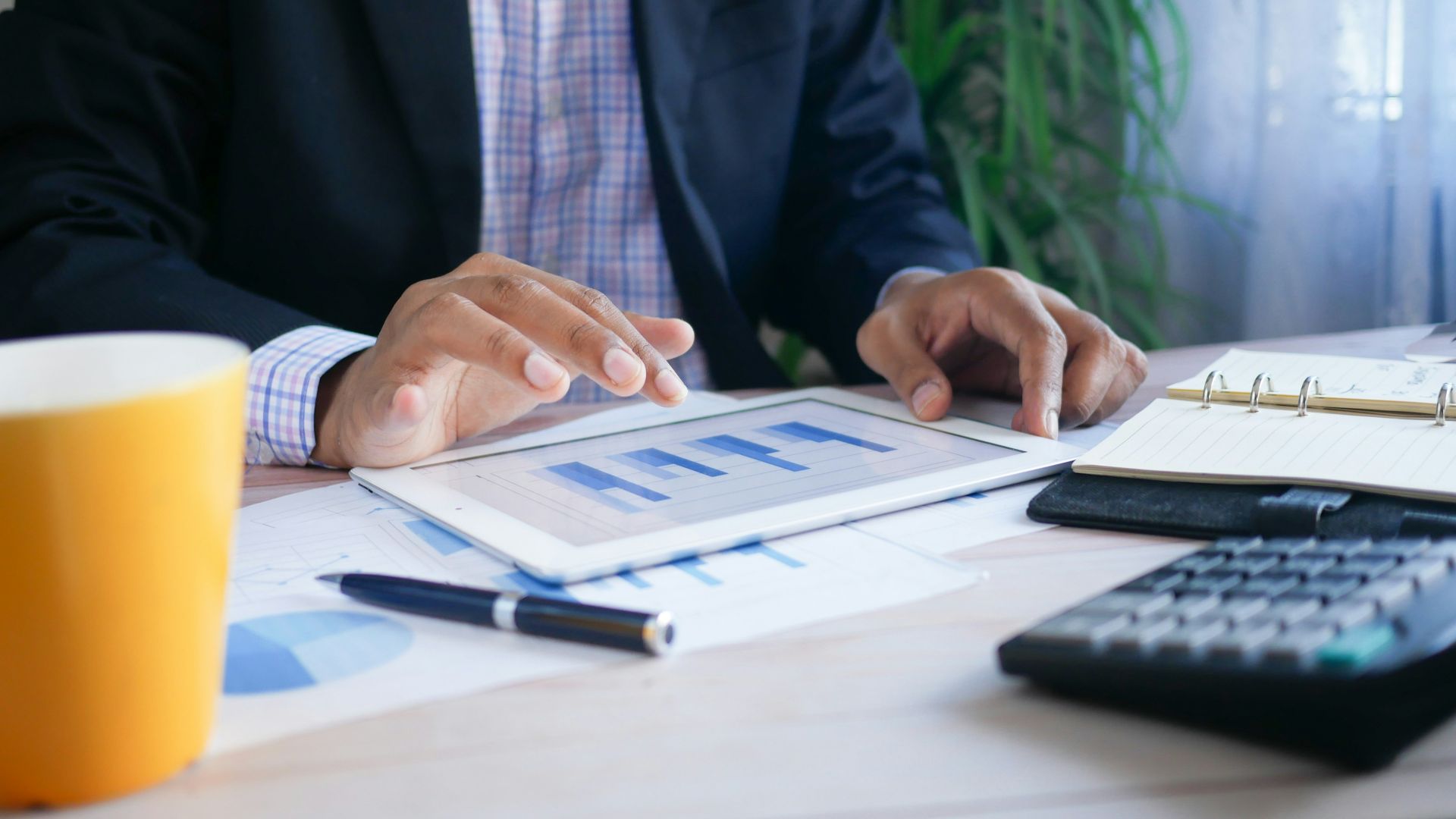 person in black suit jacket holding white tablet computer