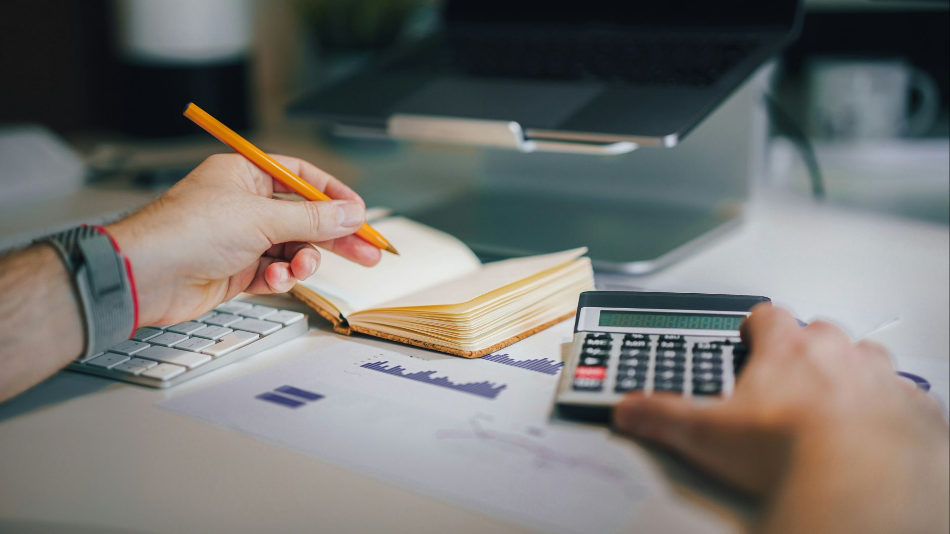 a person sitting at a desk with a calculator and a notebook