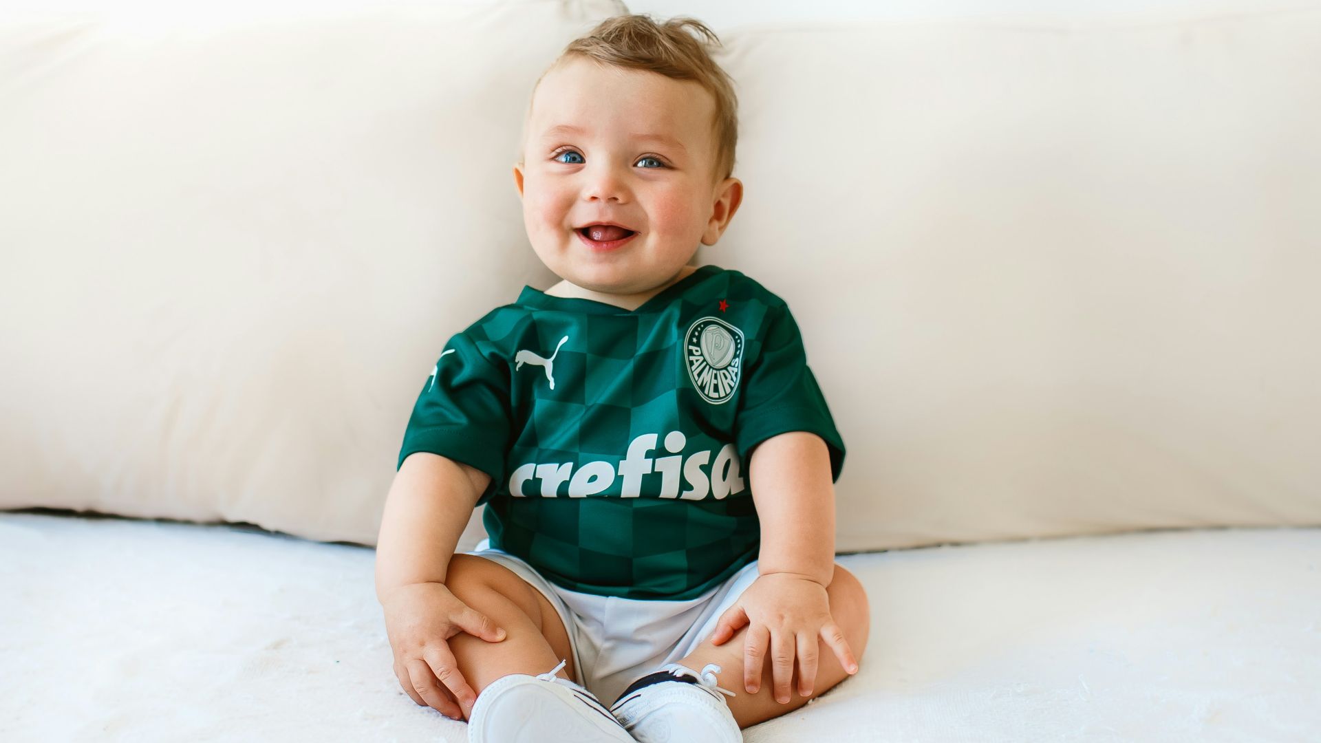 boy in green and white crew neck t-shirt sitting on white bed