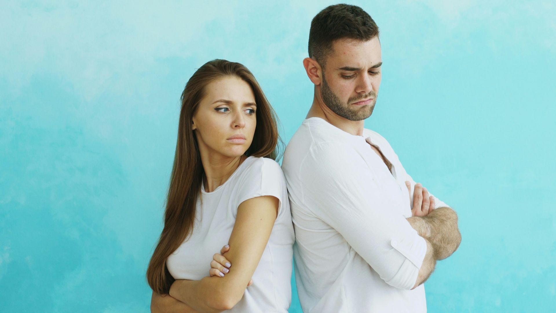 Couple standing back to back with arms crossed