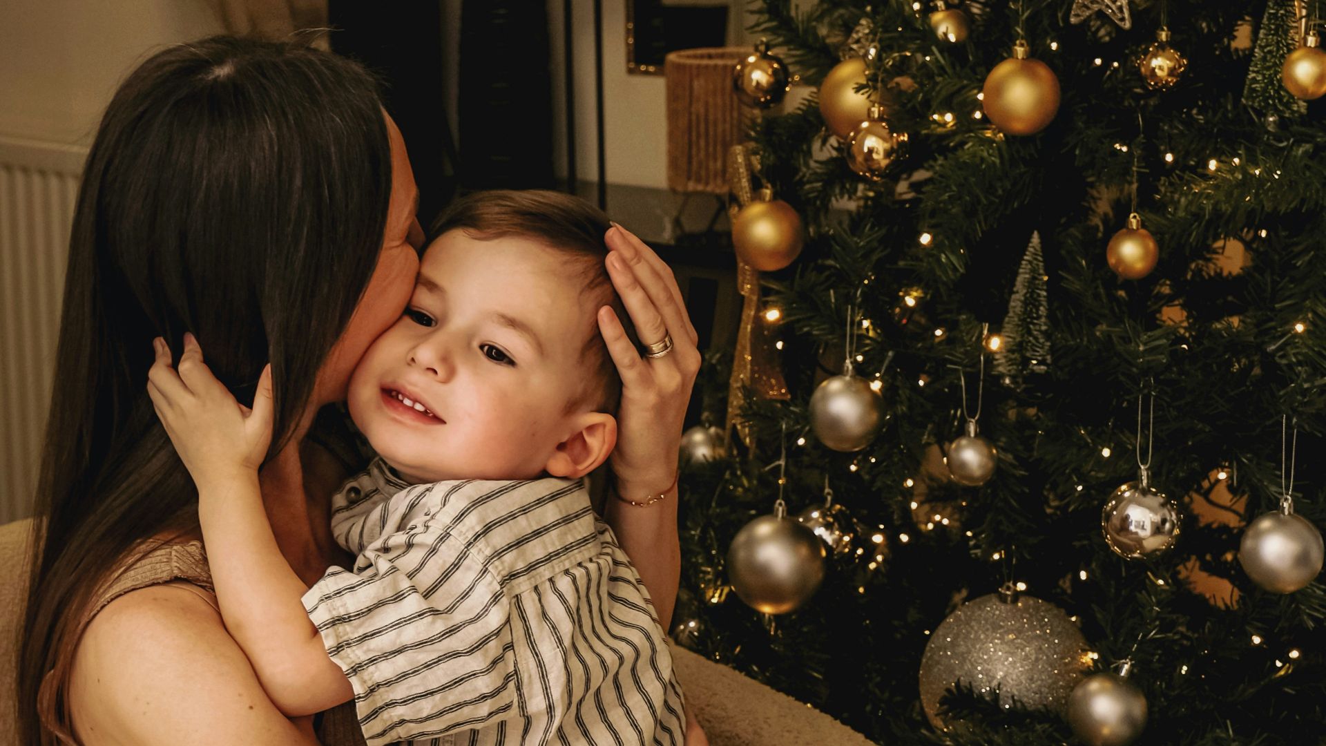 A woman holding a baby in front of a christmas tree