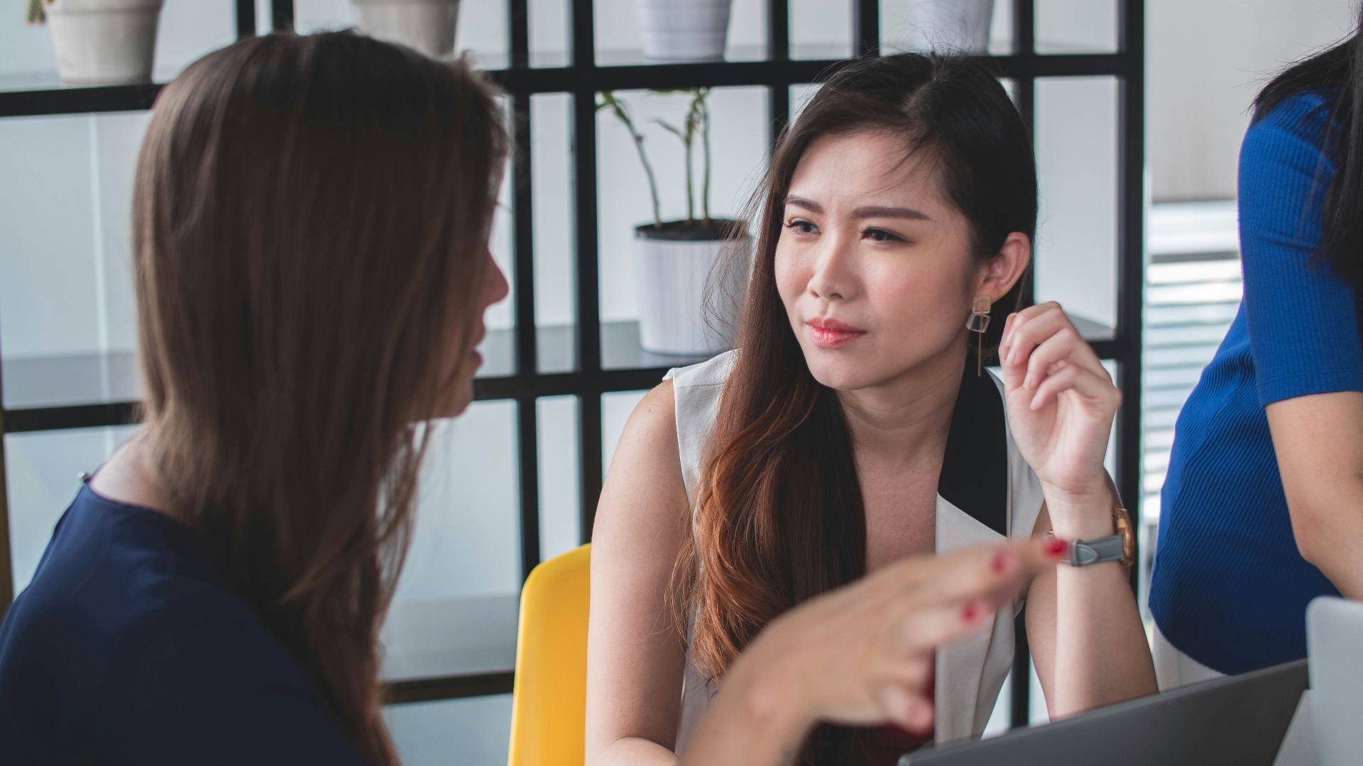 woman sitting on yellow armless chair near gray laptop computer