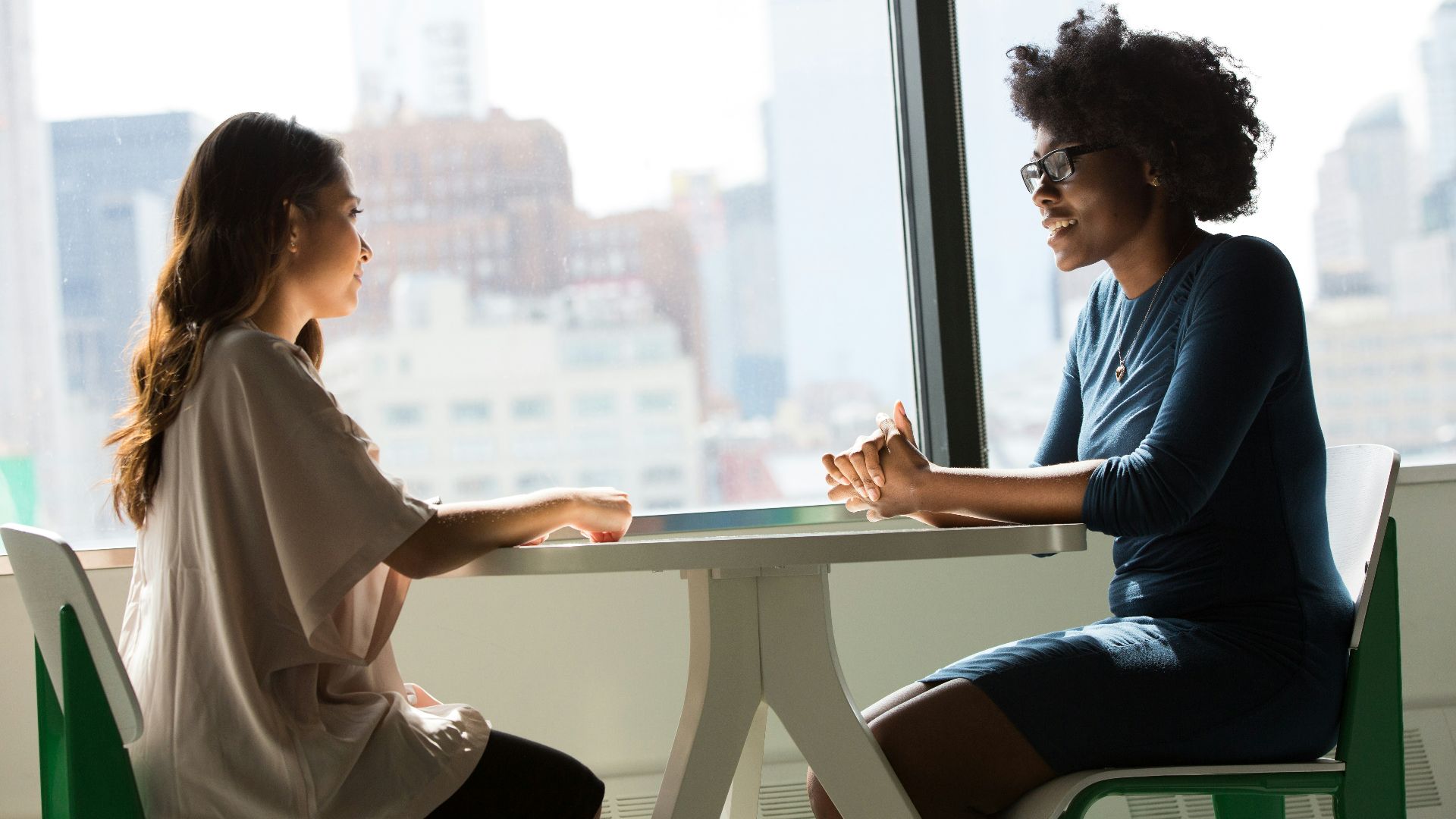 two women sitting beside table and talking