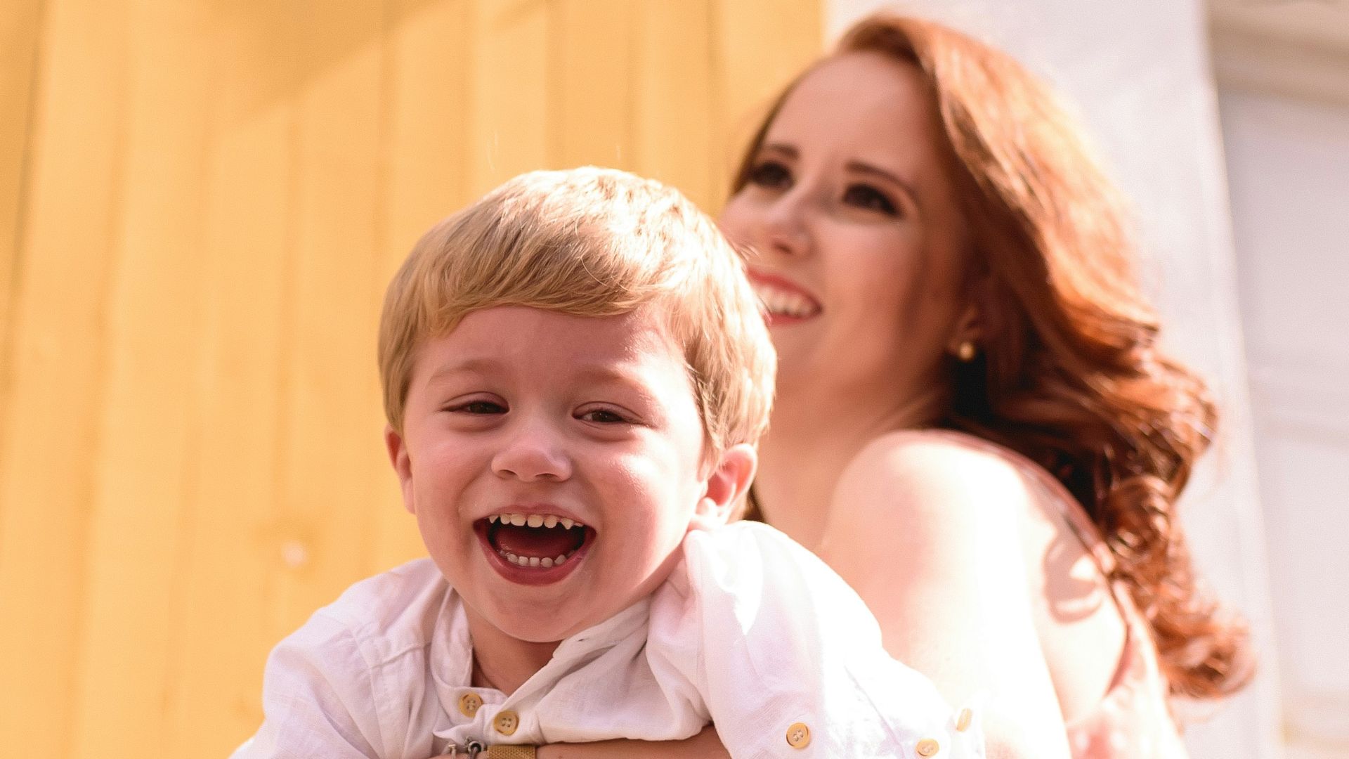 woman in blue and white plaid dress shirt carrying girl in white shirt