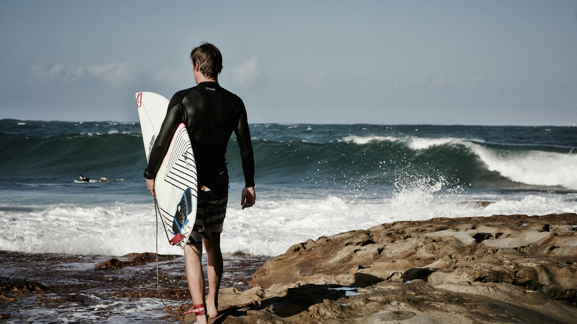 person holding surfboard near shore